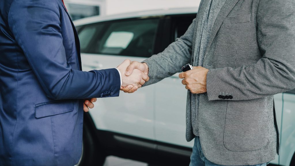 Poignée de main entre un client et un professionnel automobile.